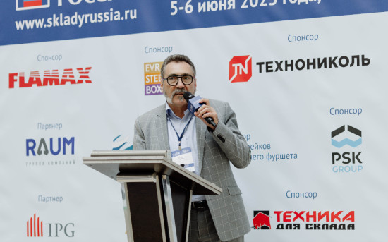 Борис Теклин, директор по техносферной безопасности Tablogix, с микрофоном на фоне логитипов участников форума Склады России