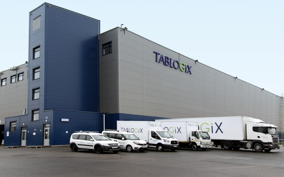 Фасад 3PL склада Tablogix d Крекшино. На фоне склада автотранспорт для грузоперевозок с логотипом Tablogix